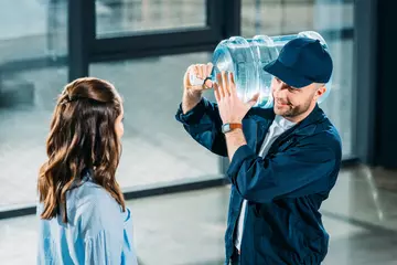 femme regardant un livreur tenant une bouteille d'eau